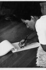 Ruby Doris Smith Robinson lays on the floor and writes on a notepad.