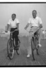 John H. Wheeler rides a bike with a young man, possibly his son.