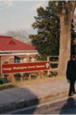 Evelyn G. Lowery (back to camera) is shown walking outside of the George Washington Carver Museum while a cameraman films.