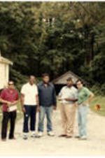 C. Eric Lincoln stands in a driveway between two houses with four other men.