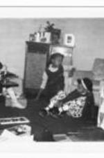 Three unidentified girls sit with Christmas presents on the floor.