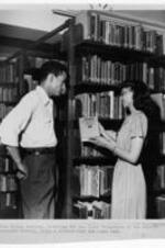 Eileen Bentley with a student in the library. Written on recto: Miss Eileen Bentley, librarian for the Negro Collection of the Atlanta University Library, helps a students find the right book. Written on verso: Atlanta University Trevor Arnett Library