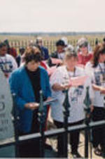Evelyn G. Lowery, Penny Liuzzo Herrington, Mary Liuzzo Lilleboe (sisters of Viola Liuzzo), Ruby Shinhoster (behind Lowery), and SCLC/W.O.M.E.N. Civil Rights Heritage Tour participants are shown reading a litany at Viola Liuzzo's memorial marker.