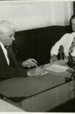 John H. Wheeler and C.C. Spaulding sit at Spaulding's desk and talk.