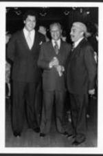 Maynard Jackson stands and talks with two other men at a reception.