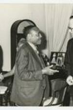 Edward A. Jones speaks with an unidentified man while people in the background shake hands.