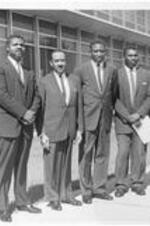 Dr. Harry V. Richardson (second from left), Dr. Isaac Clark, and students including Charles Blake stand outside the ITC classroom building. Written on verso: President Richardson, Isaac Clark, &amp; ITC Students, Matriculation Day 10/09/1962.