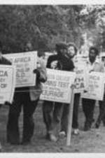 A group of Augusta College students are shown protesting against apartheid. Written on verso: SCLC Condemns Apartheid -- Several community supporters and a few whites in Augusta, Georgia join protest at Augusta College October 14th to voice disapproval of the appearance there of a South African boys' choir.