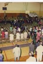 Indoor view of faculty procession in a gymnasium.