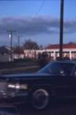 Cars drive past the Mallory House. Unknown location.