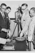 A group of men examine audio equipment. Written on verso: Seminar for Superintendents, 1951. Dr. B.F. Jackson, of the audio-visual department, the board of education, Nashville, TN gives demonstration in modern techniques to a group district superintendents in attendance at a seminar for superintendents at Gammon.