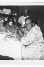 An unidentified woman sits at a dining room table.