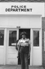 A policewoman stands in front of the police department.