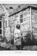 Mrs. Helen C. Shorts standing in front of a brick house. Written on verso: Mrs. Helen C. Shorts at Mrs. E.S. Davis' home Madrona N.W. Atlanta, Georgia.