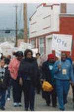 Evelyn G. Lowery (second from right) marches with other SCLC/W.O.M.E.N. Civil Rights Heritage Tour participants holding signs advocating for voting and voter registration.