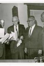 Benjamin Mays stands with three other men wearing suits holding papers.