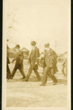 Three unidentified men walking and wearing hats.