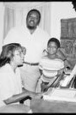 C. Eric Lincoln stands around the piano and sings with his family at home.