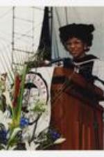 Reatha Clark King stands at the podium on stage at commencement.