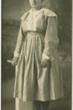 Portrait of an unidentified girl standing next to a pedestal.