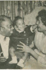 Graham W. Jackson Sr. and his wife look at a smiling baby resting on the arm of a couch.
