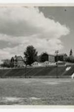 View of stadium bleachers from football field, view of building and clock tower in background.