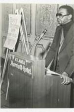 View of a man at podium and sign, on podium: Atlanta Marriott Hotel. Written on verso: "Mr. Marsh King, Director of Upward Bound, Special Services, c. early 1980s".