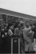 Spiver Gordon (first on right on the dais) is shown speaking at a rally alongside Southern Christian Leadership Conference President Joseph E. Lowery (third from left) and others in Selma, Alabama. Written on verso: SCLC Board Member Spiver Gordon speaks [illegible] rally at [illegible] High School in Selma, Alabama.