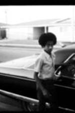 An unidentified boy and woman stand next to a Cadillac car.