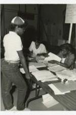View of young women are table. Written on verso: "A Freshman at registration 1984".