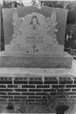 A photo of Jimmie Lee Jackson's headstone that shows bullet holes pock marking the surface.
