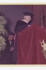 A man stands behind a podium on stage at commencement.