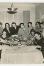 Indoor view of women around a dining table looking at fabrics.