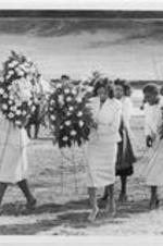 Women carry floral arrangements to the gravesite as part of the funeral proceedings for Dr. Randolph T. Blackwell.