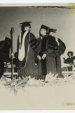 Indoor view of men wearing graduation cap and gown. Written on verso: conferring Honorary degree, Dr. James H. Touchstone, June 1965.
