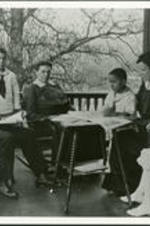 George A. Towns and family listen to a child read a book on the porch.
