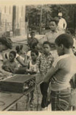 Children look on as a young woman sets up music for the "Safe Summer 1981" program. For more details about the "Safe Summer" program, see pages 39-43 of the August-September 1981 SCLC Magazine: http://hdl.handle.net/20.500.12322/auc.199:07019.