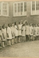 A large group of children gather outside in a formation.