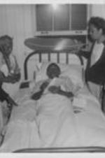 A man lays in bed surrounded by women at the at the Happy Haven Nursing Home, now named Sadie G. Mays Health and Rehabilitation Center.