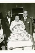 President Hugh Gloster stands with Benjamin Mays and a woman behind a large cake.
