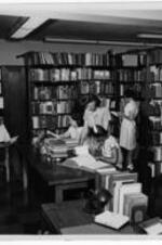 Eileen Bentley helping students in the library. Written on verso: Negro Collection Trevor Arnett Library c1950