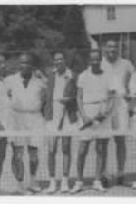 A group of men stand on a tennis court holding rackets.