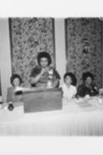 An unidentified woman is shown speaking at the SCLC/WOMEN breakfast event held as part of the proceedings during the 23rd Annual Southern Christian Leadership Conference Convention. Written on verso: SCLC/WOMEN Breakfast. Cleveland Conv. Aug., 1980