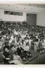View of audience in the Fine Arts Auditorium in 1968. Left, front row, 4th from right, floral skirt-Quinta Hollam; left, front row, 4th from right, black skirt-Carolyn Meyers; 2nd row, far left, kneeling, white shirt-Jocelyn Rutledge; Middle left row from the front, white and Black Blazer-Judith Sells; Far left, 3rd row,  3rd from center, black glasses- Rosalyn Yancy; Far left 2nd row, end of row, glasses-Gloria Cook. Far right, right section toward the back Dr. Roland Nelison, Dr. Denise Holloway.