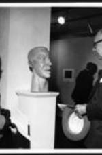 An unidentified man and woman admire a sculpture of a human head.