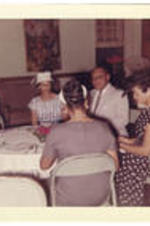 People sit around a table at the Beta Phi Mu initiation ceremony.
