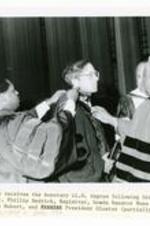 Written on recto: Senator Sam Nunn receives the honorary LL. D. degree following his Founder's Day address. Dr. Phillips Redrick, Registrar, hoods Senator Nunn as Academic Dean, Dr. Willis Hubert, and President Gloster (partially hidden) look on. Founder's Day, 1982.