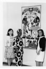 Dorathy Ku, Josephine Richards, &amp; Casuo stand in front of an Egyptian themed quilt hanging on a wall. Written on verso: Dorathy Ku, Josephine Richards, Casuo.