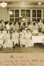 A group of women gather at a table filled with cakes and flowers. Written on recto: May 27, 1933. Anniversary celebrating Miss Chadwick's thirtieth year of service in the Leonard Street Orphan Home.