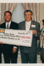 Southern Christian Leadership Conference (SCLC) President Joseph E. Lowery and Claud Young are shown receiving a check from James B. Adamson (standing between Lowery and Young). Written on verso: Dr. Joseph E. Lowery - President &amp; CEO, SCLC; Dr. Claude Young - Chairman of the Board of Directors, SCLC; Adamson, Flagstar CEO